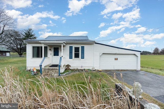 view of front of property featuring a garage, metal roof, driveway, and a front lawn