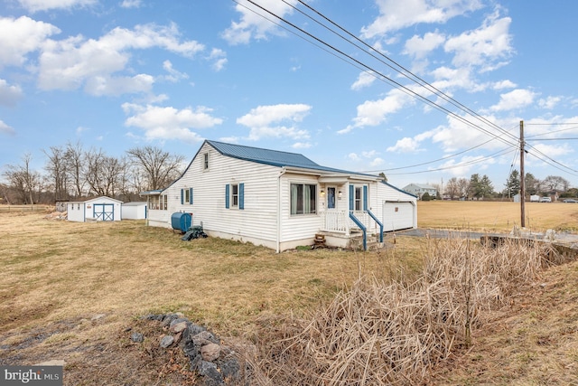 view of front of house featuring metal roof, a front lawn, an outdoor structure, and a shed