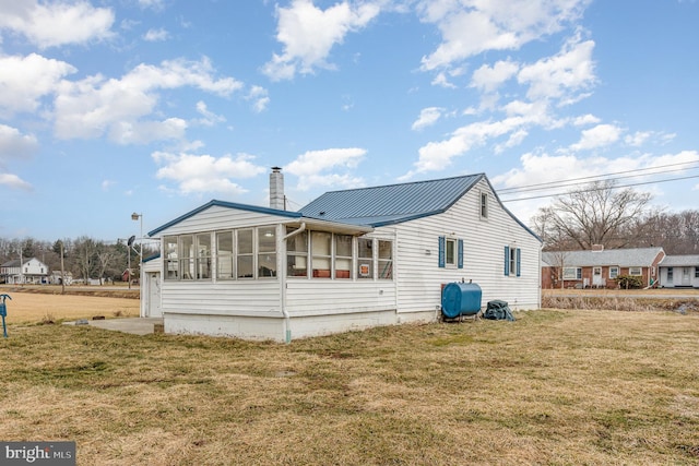 rear view of house with a yard, a chimney, a sunroom, and heating fuel