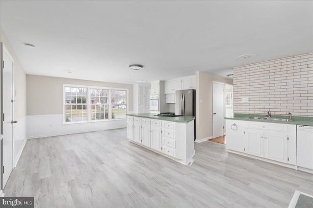 kitchen featuring light wood-type flooring, white appliances, white cabinetry, and sink