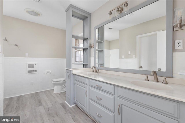 bathroom with hardwood / wood-style floors, vanity, toilet, tile walls, and heating unit