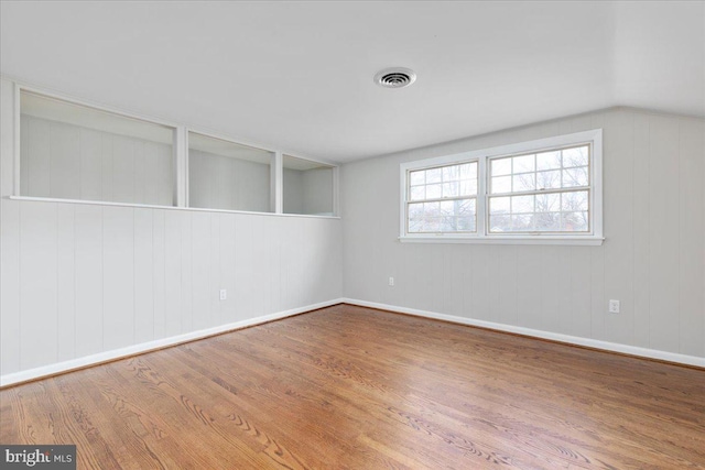 spare room featuring hardwood / wood-style flooring, lofted ceiling, and wooden walls