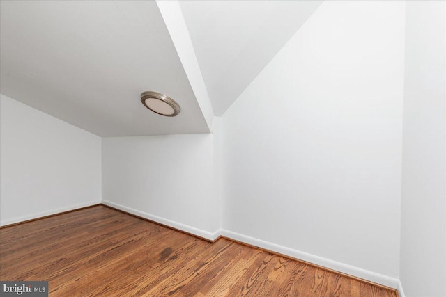 bonus room with hardwood / wood-style flooring and vaulted ceiling