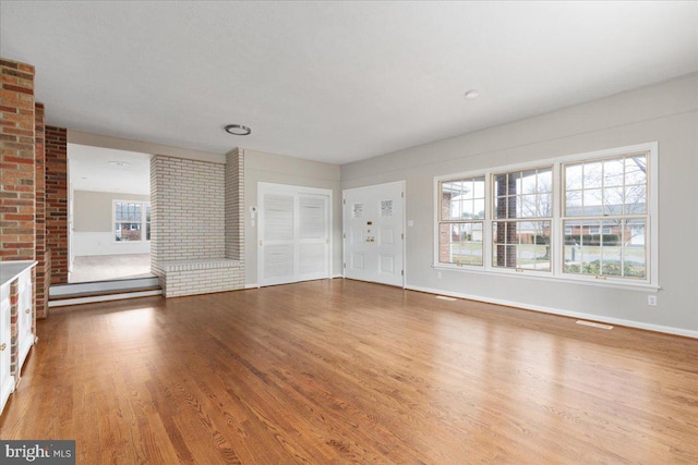 unfurnished living room with a large fireplace and light hardwood / wood-style flooring