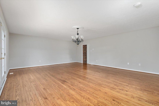 empty room featuring a chandelier and light wood-type flooring