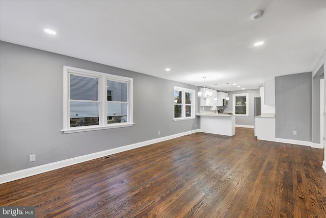 unfurnished living room featuring dark hardwood / wood-style floors and a chandelier