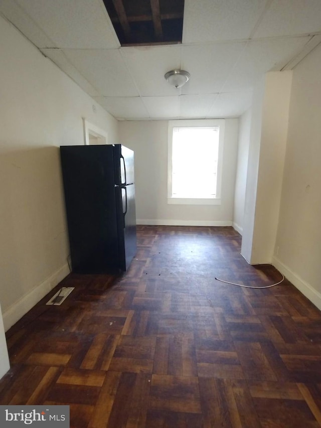 kitchen with black refrigerator, a drop ceiling, and dark wood-type flooring