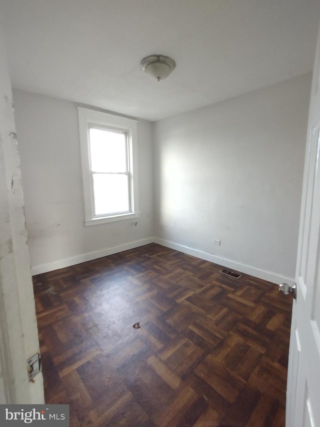 spare room with dark parquet floors