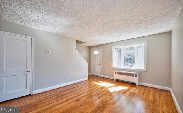 entryway featuring radiator heating unit, a textured ceiling, and light hardwood / wood-style flooring