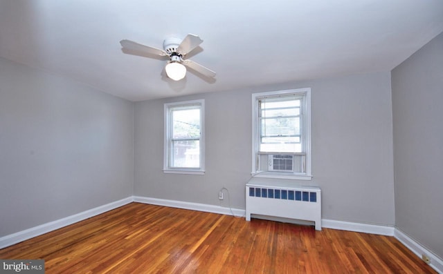 unfurnished room with radiator, ceiling fan, and dark wood-type flooring