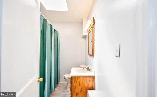 bathroom with tile patterned flooring, vanity, a skylight, and toilet