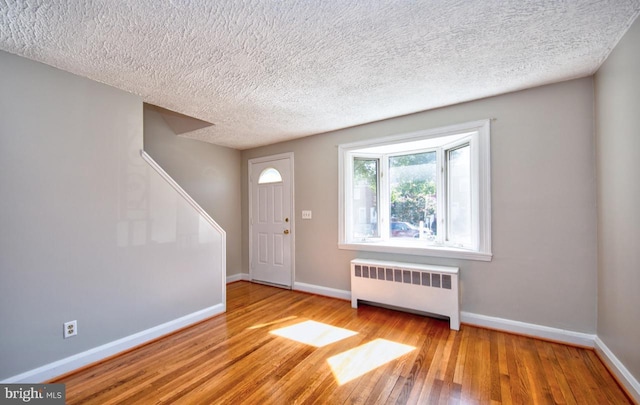 foyer featuring light hardwood / wood-style floors, a textured ceiling, and radiator