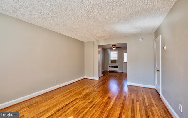 spare room with hardwood / wood-style floors, ceiling fan, a textured ceiling, and radiator