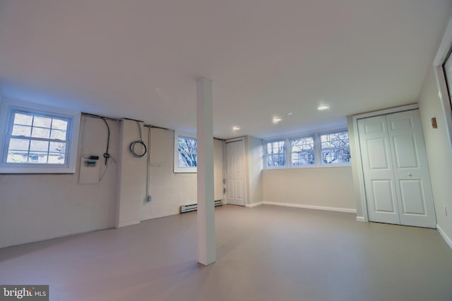 basement featuring a baseboard heating unit and a wealth of natural light