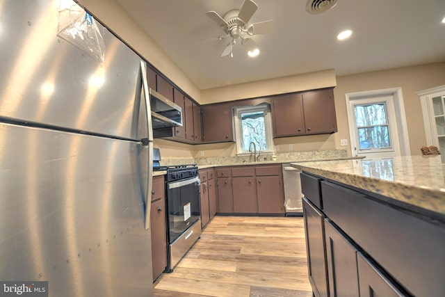 kitchen with stainless steel appliances, light stone countertops, sink, and plenty of natural light