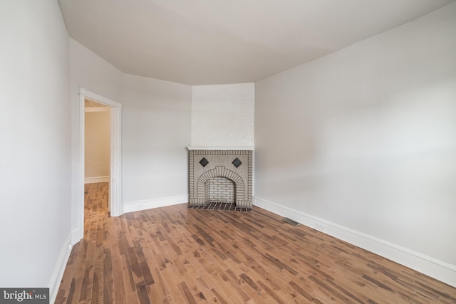 unfurnished living room with hardwood / wood-style floors and a brick fireplace