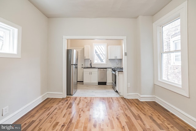 kitchen with white cabinets, stainless steel appliances, a wealth of natural light, and sink