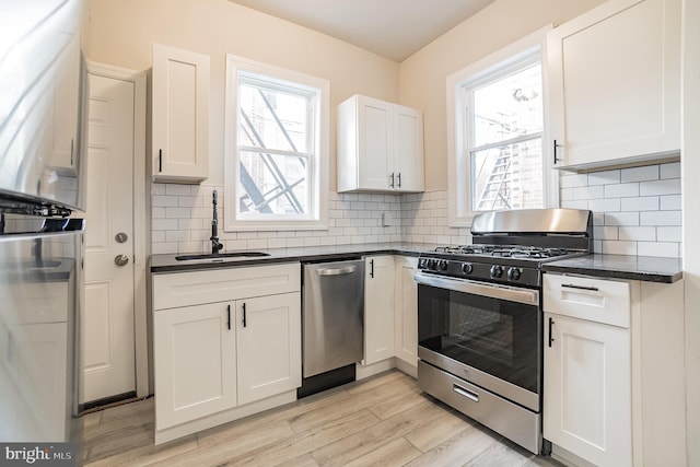 kitchen with white cabinetry, sink, tasteful backsplash, light hardwood / wood-style floors, and appliances with stainless steel finishes