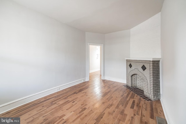 unfurnished living room with hardwood / wood-style floors and a brick fireplace