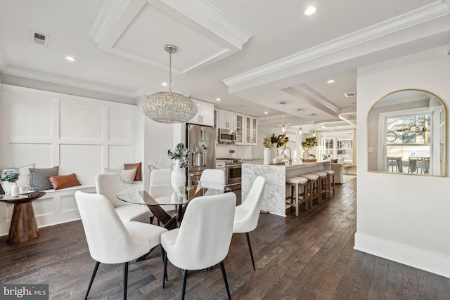 dining room featuring sink, dark wood-type flooring, a notable chandelier, and ornamental molding