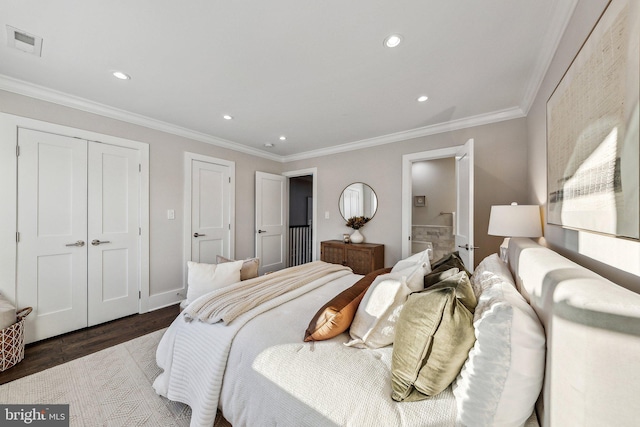 bedroom featuring connected bathroom, crown molding, a closet, and dark wood-type flooring