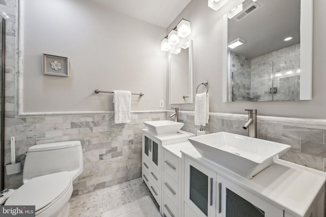 bathroom featuring walk in shower, tile patterned flooring, toilet, vanity, and tile walls