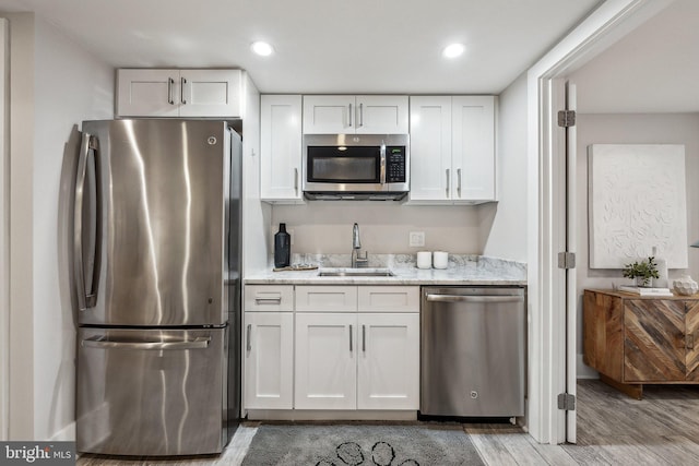 kitchen featuring sink, white cabinets, stainless steel appliances, and hardwood / wood-style flooring