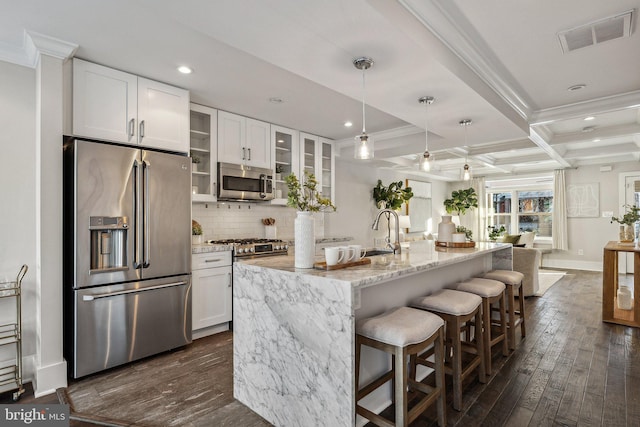 kitchen with light stone countertops, appliances with stainless steel finishes, coffered ceiling, beamed ceiling, and white cabinetry