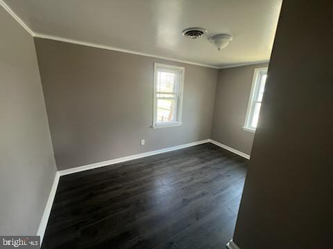 empty room featuring dark hardwood / wood-style floors and crown molding