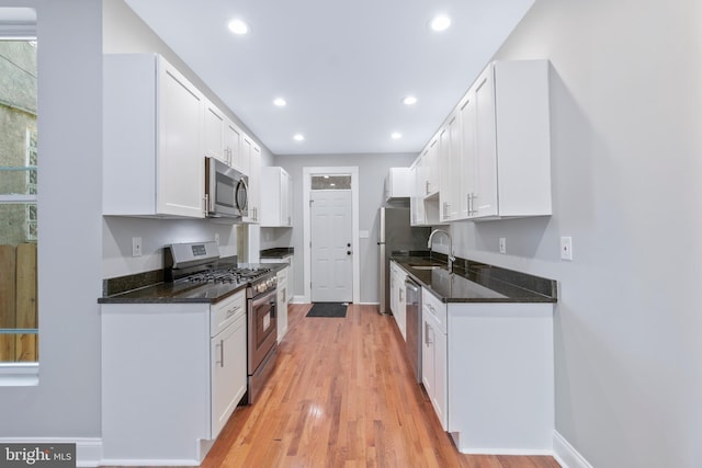 kitchen featuring stainless steel appliances, white cabinetry, light hardwood / wood-style floors, and sink