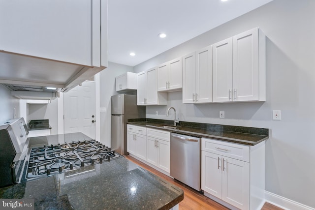 kitchen with sink, white cabinets, light wood-type flooring, and appliances with stainless steel finishes