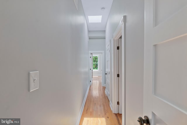 corridor featuring light hardwood / wood-style floors and a skylight