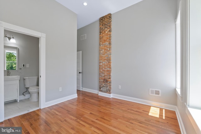 unfurnished bedroom with light wood-type flooring, sink, and ensuite bath