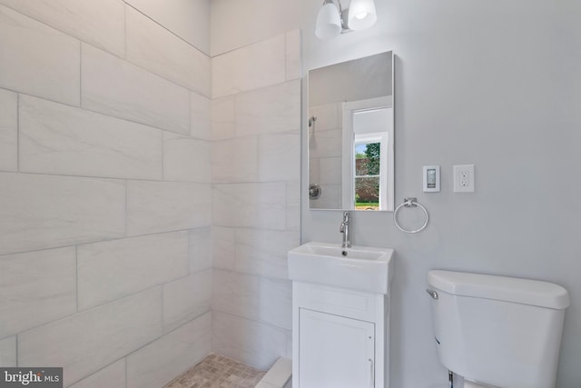 bathroom with tiled shower, vanity, and toilet