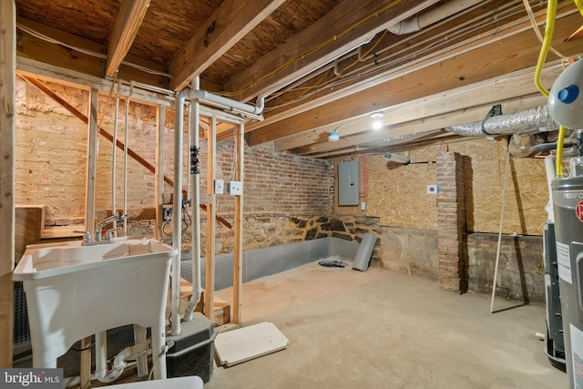 basement featuring sink, electric panel, water heater, and brick wall