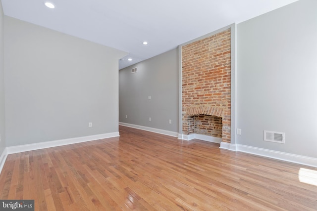 unfurnished living room with a brick fireplace and light hardwood / wood-style flooring