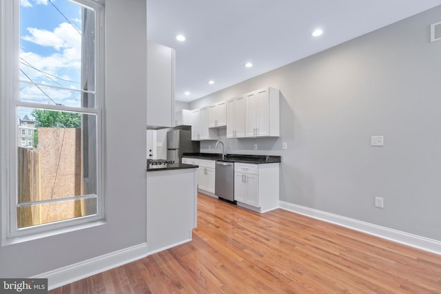 kitchen with sink, white cabinets, light wood-type flooring, and appliances with stainless steel finishes