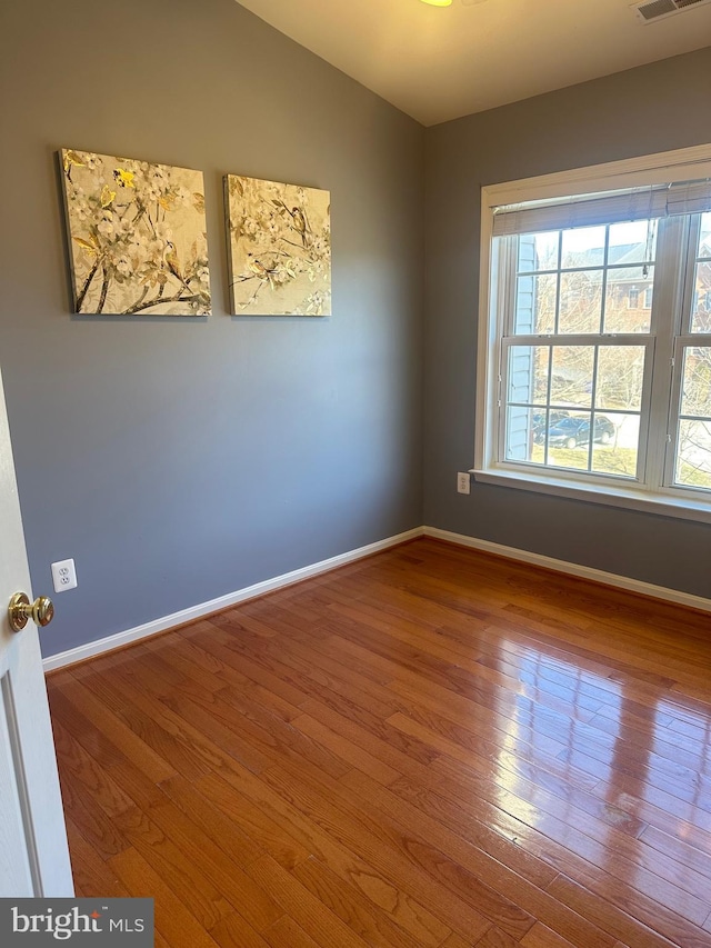 spare room featuring lofted ceiling and wood-type flooring