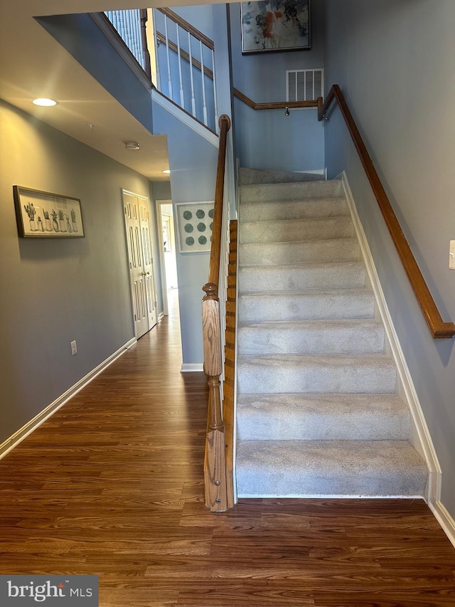 stairway with a towering ceiling and hardwood / wood-style floors