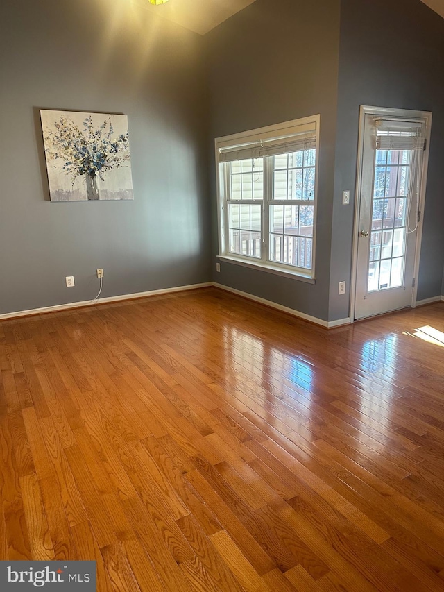 spare room with light hardwood / wood-style floors and a high ceiling