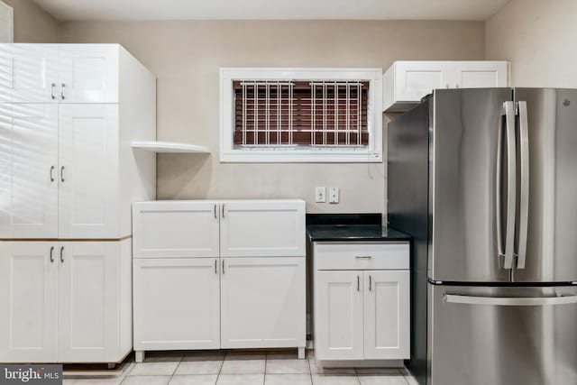 kitchen with white cabinets, light tile patterned floors, and stainless steel refrigerator