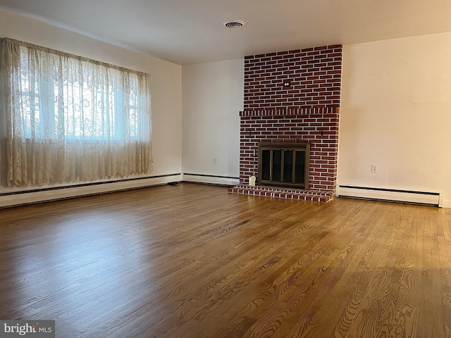 unfurnished living room with a brick fireplace, hardwood / wood-style floors, and a baseboard heating unit