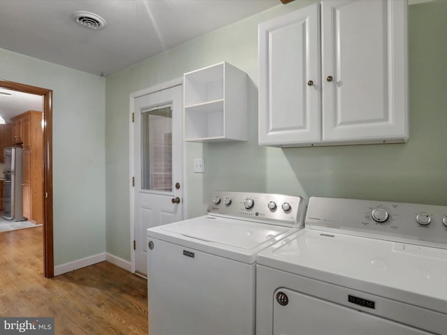 washroom featuring cabinets, light wood-type flooring, and separate washer and dryer