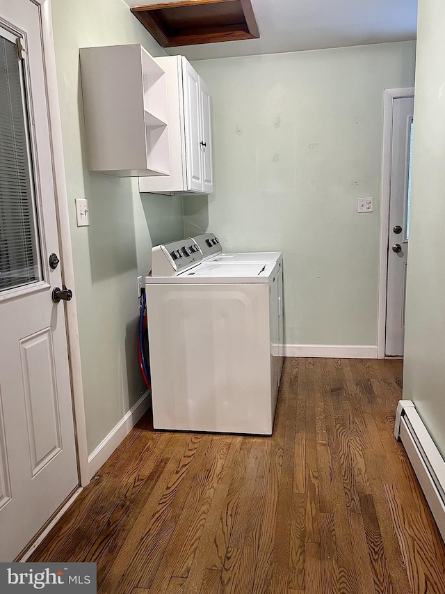 clothes washing area with cabinets, dark hardwood / wood-style floors, washing machine and dryer, and baseboard heating