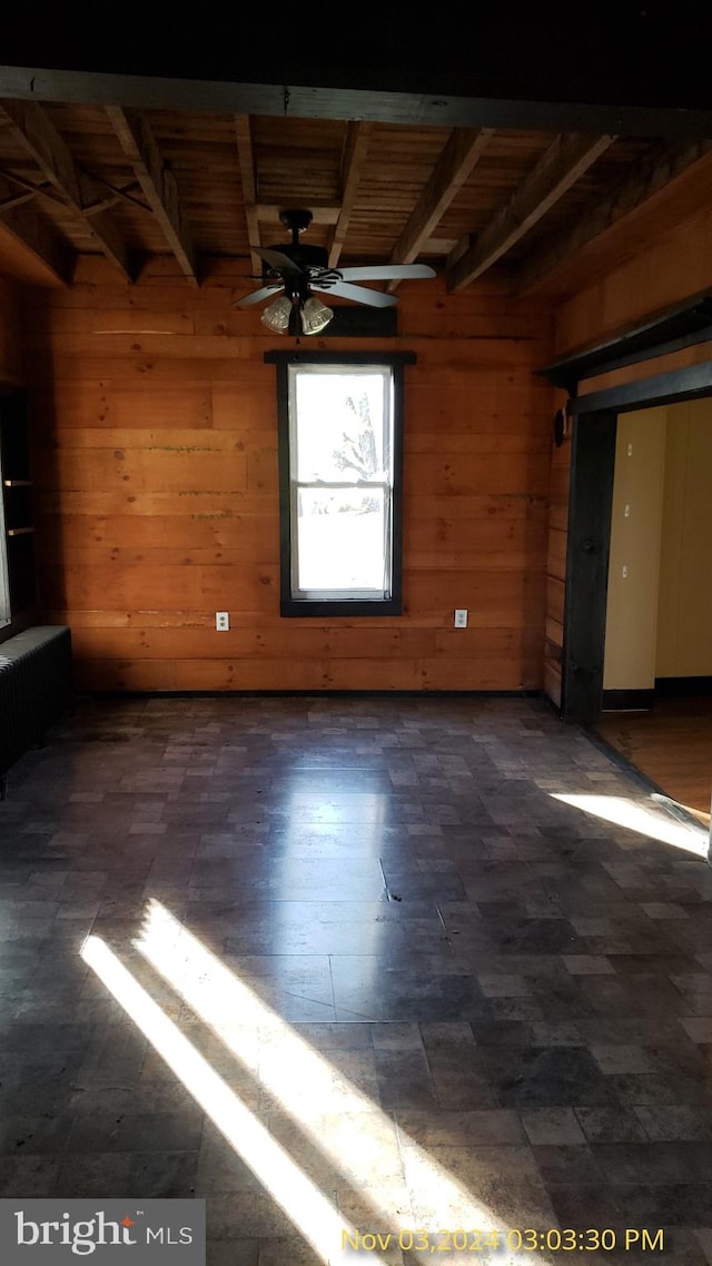 unfurnished room with wood walls, wooden ceiling, beam ceiling, and radiator