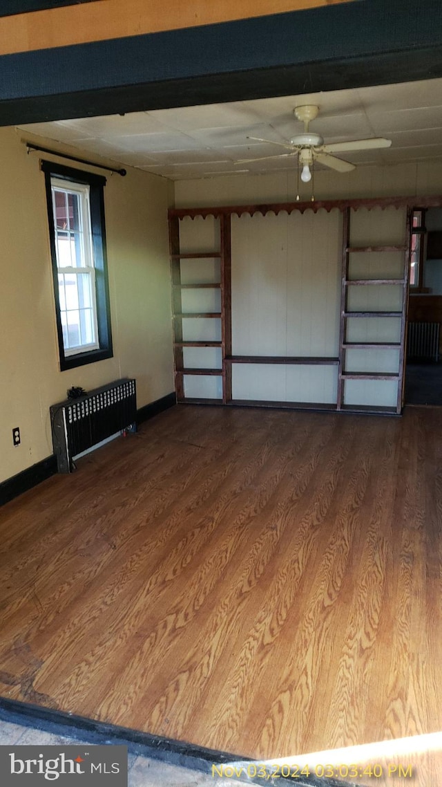 interior space with radiator heating unit, ceiling fan, and wood-type flooring