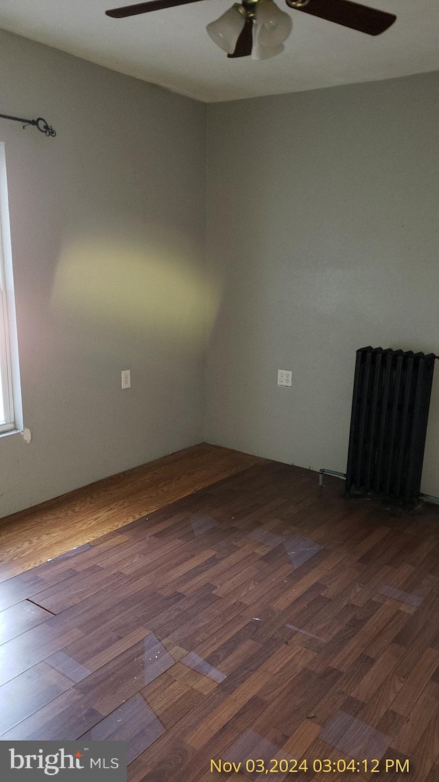 spare room featuring dark hardwood / wood-style floors and radiator