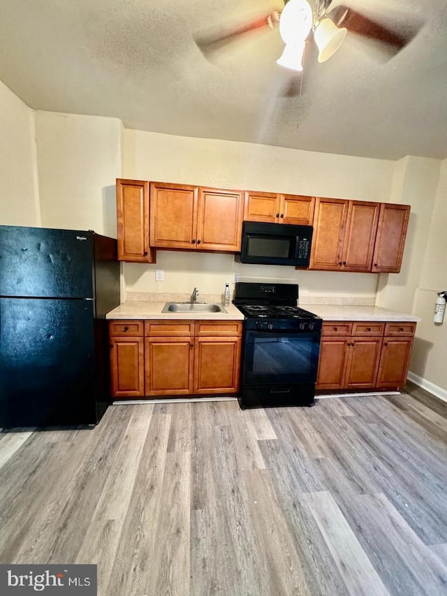 kitchen with black appliances, ceiling fan, light hardwood / wood-style floors, and sink