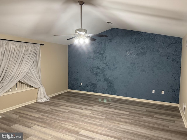 spare room with wood-type flooring, vaulted ceiling, and ceiling fan