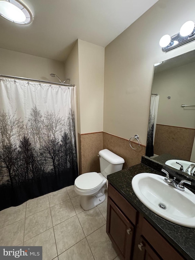 bathroom with tile patterned floors, vanity, tile walls, and toilet